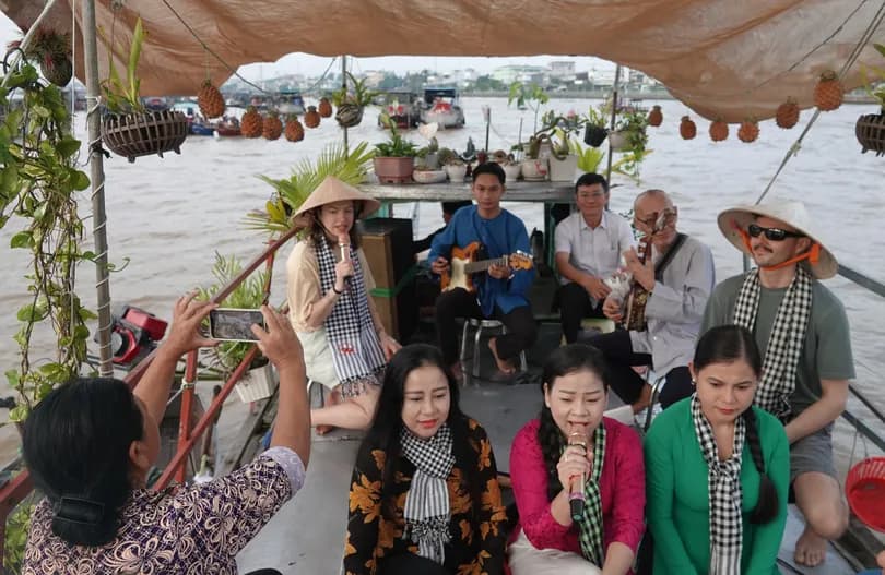 Foreign tourists enjoy listening to traditional Vietnamese folk music at Cai Rang Floating Market.